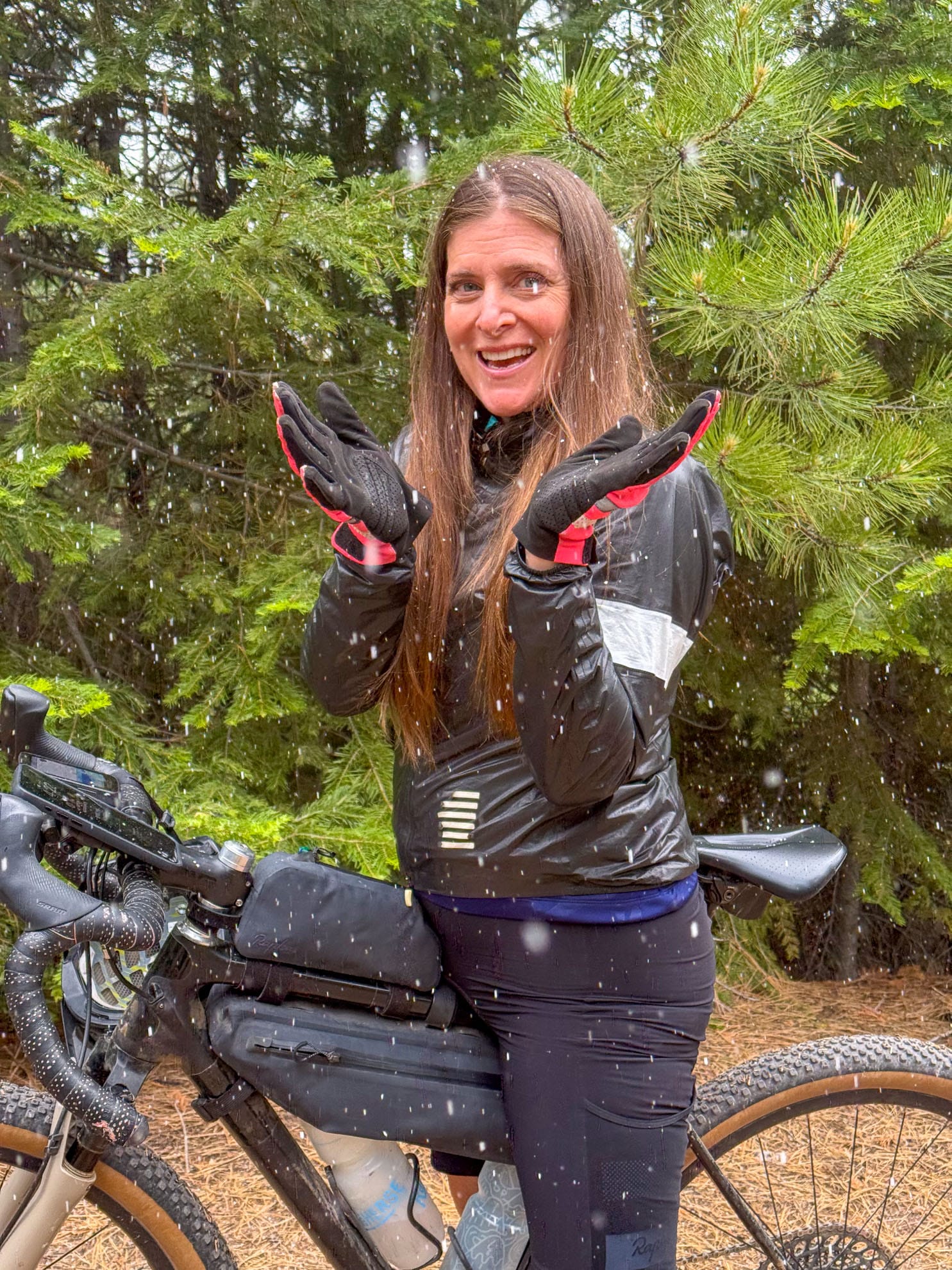 Woman on bicycle with summer snow falling in a forest