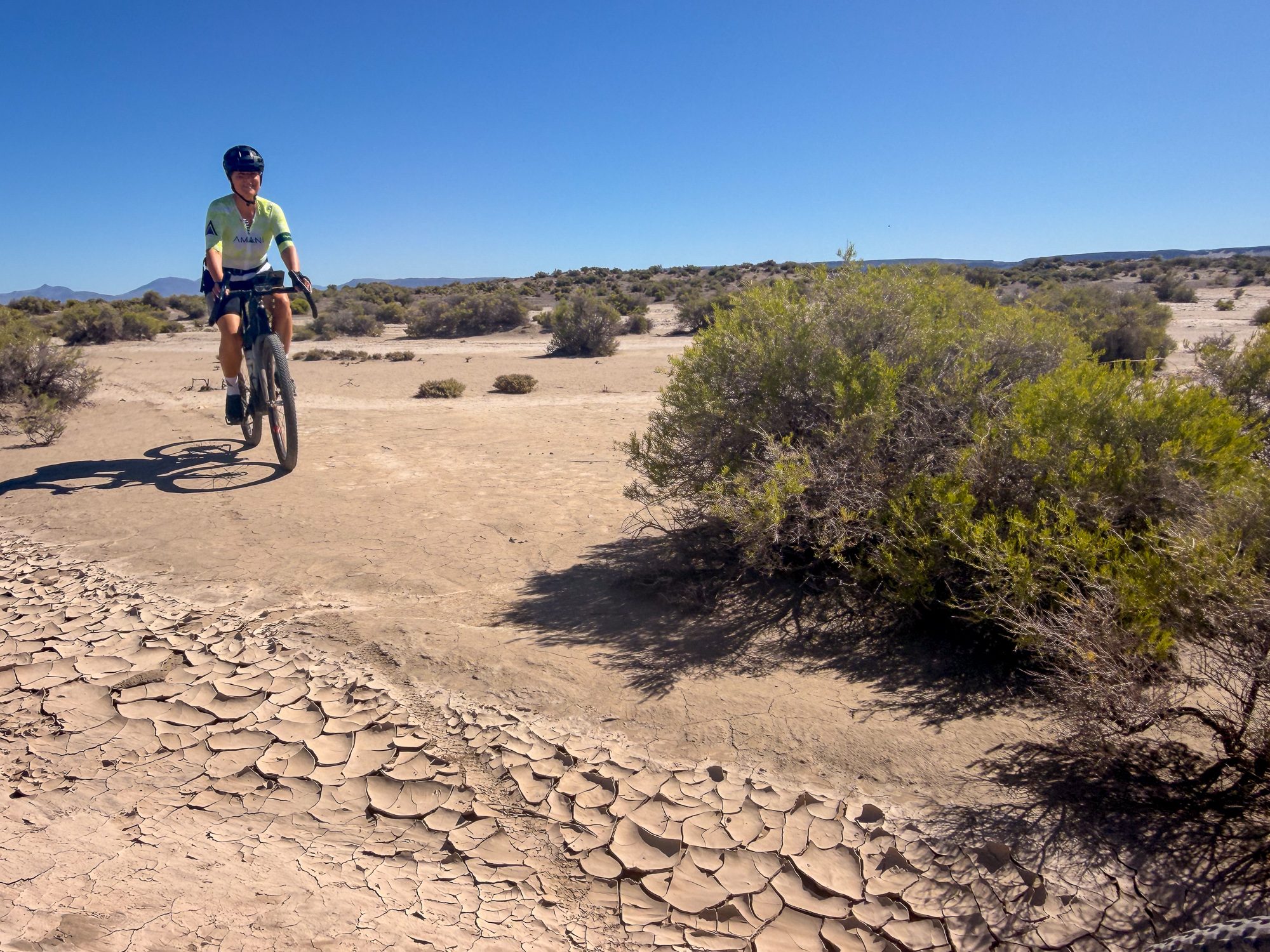 Amy riding across cracked dry mud near the sagebrush edge